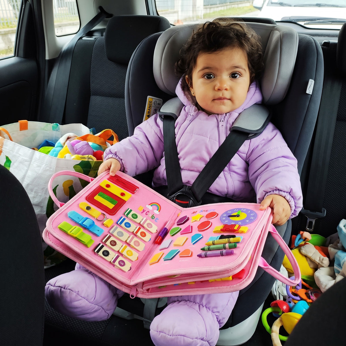 Bambina in macchina con il busy board Somnalis rosa
